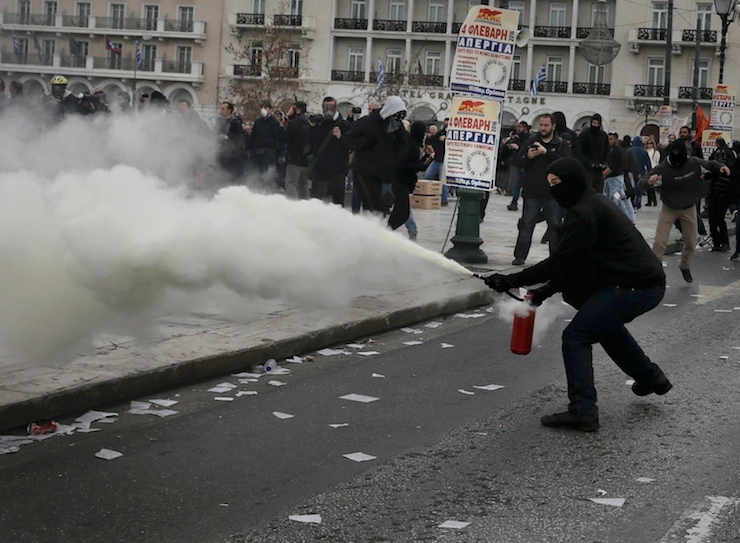 A masked demonstrator sets off a fire extinguisher during clashes with riot police during a 24-hour general strike against planned pension reforms in Athens