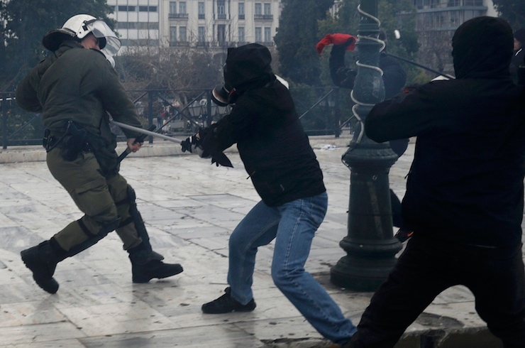 A masked demonstrator clashes with a riot police officer during a 24-hour general strike against planned pension reforms in Athens