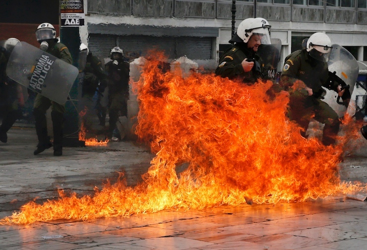 Riot police react to petrol bombs during a 24-hour general strike against planned pension reforms in Athens