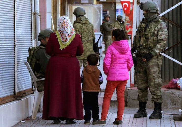 A woman with children talks to soldiers in Baglar district, which is partially under curfew, in the Kurdish-dominated southeastern city of Diyarbakir