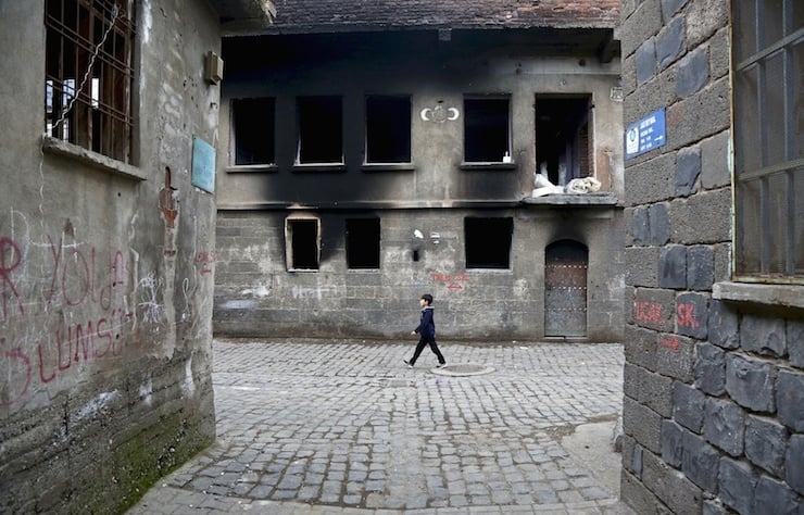 A boy walks past by a damaged building in Sur district, which is partially under curfew, in the Kurdish-dominated southeastern city of Diyarbakir