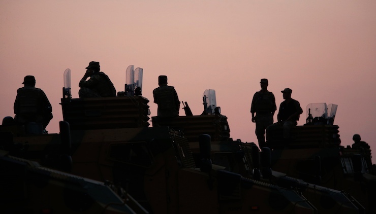 Turkish soldiers are silhouetted as they stand on top of armoured vehicles near the Mursitpinar border crossing on the Turkish-Syrian border, in the southeastern Turkish town of Suruc in Sanliurfa province October 3, 2014. Kurdish fighters defending a Syrian border town warned on Friday of a likely massacre by Islamic State insurgents as the Islamists encircled the town with tanks and bombarded its outskirts with artillery fire. Turkey said it would do what it could to prevent Kobani, a predominantly Kurdish town just over its southern border, from falling into Islamic State hands but stopped short of committing to any direct military intervention. REUTERS/Murad Sezer (TURKEY - Tags: MILITARY POLITICS CIVIL UNREST CONFLICT TPX IMAGES OF THE DAY) - RTR48UC5