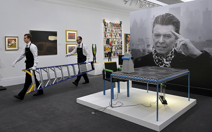 Technicians carry a ladder as they prepare for the exhibition of British pop star David Bowie's art collection at Sotheby's auction house, in central London