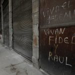 A woman walks past a graffiti that reads “Long live Fidel and Raul” in Havana, Cuba