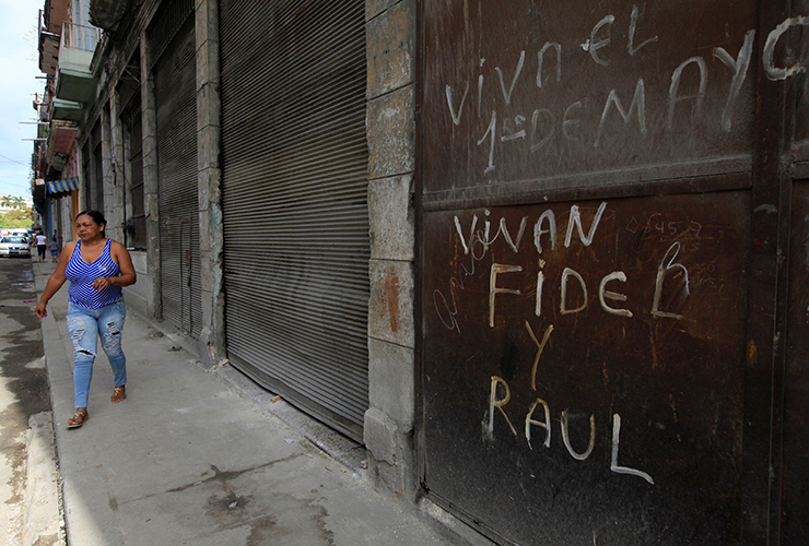 A woman walks past a graffiti that reads "Long live Fidel and Raul" in Havana, Cuba