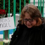 A woman reacts next to a placard and flowers as part a tribute outside the Cuban Embassy in Mexico, following the announcement of the death of Cuban revolutionary leader Fidel Castro, in Mexico City