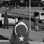 People gather with Turkish flags near the scene of Saturday's blasts in Istanbul, Turkey