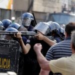Policeman aims a weapon during a demonstration against a possible change in the law to allow for presidential re-election in front of the Congress building in Asuncion