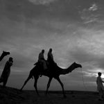 File photo of tourists riding camels as they are silhouetted against the setting sun over the Thar Desert at Sam village