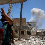 A displaced Iraqi resident carries his child overlooking a smoke billowing due to fighting between Iraqi forces and Islamic State militants near the Old City in western Mosul