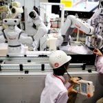 Staff program a robot arm by Nachi Robotic Systems at the International Robot Exhibition in Tokyo