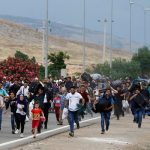 Syrians carry their belongings as they walk to the Turkish Cilvegozu border gate in the southern Hatay province
