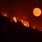 The full moon rises over flames of the Alamo fire on a hilltop off Highway 166 east of Santa  Maria