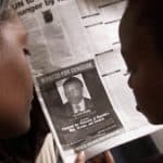 READERS LOOK AT A PICTURE OF A RWANDAN WANTED FOR THE ALLEGEDMASTERMIND OF RWANDA'S 1994 GENOCIDE.