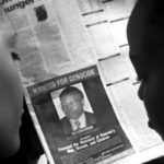 READERS LOOK AT A PICTURE OF A RWANDAN WANTED FOR THE ALLEGEDMASTERMIND OF RWANDA'S 1994 GENOCIDE.