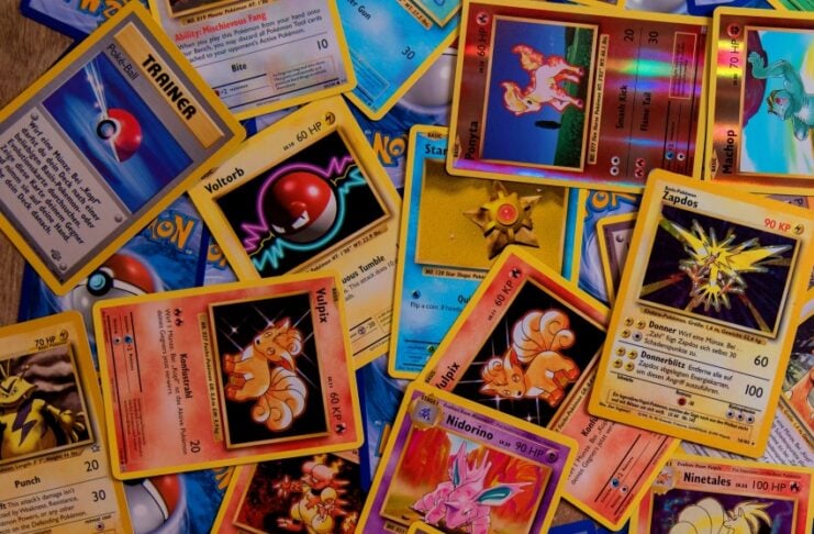 A colorful jumble of Pokémon trading cards scattered on a blue game mat, showing various characters and trainer cards.