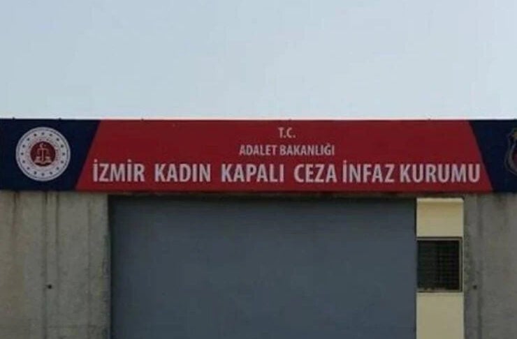 Entrance to Izmir Kadın Kapalı Ceza İnfaz Kurumu, a Turkish women’s prison, with a large gray rolling door beneath a red sign on top.