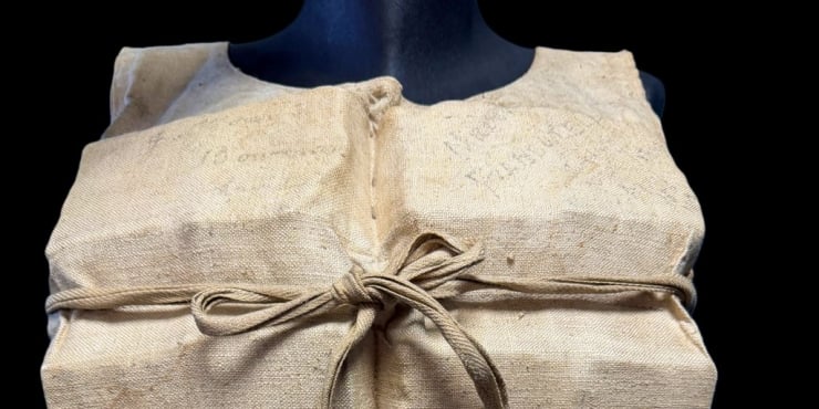 Mannequin torso wearing a burlap garment tied with a rope belt, close-up view.
