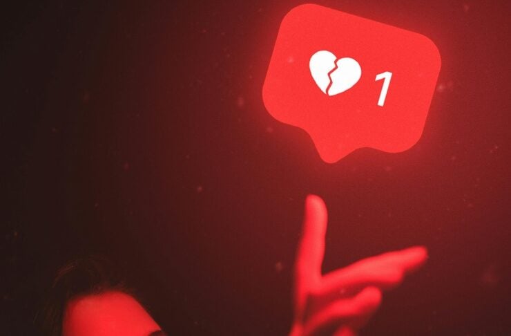Young woman reaching toward a glowing red notification bubble showing a broken-heart icon and the number 1.