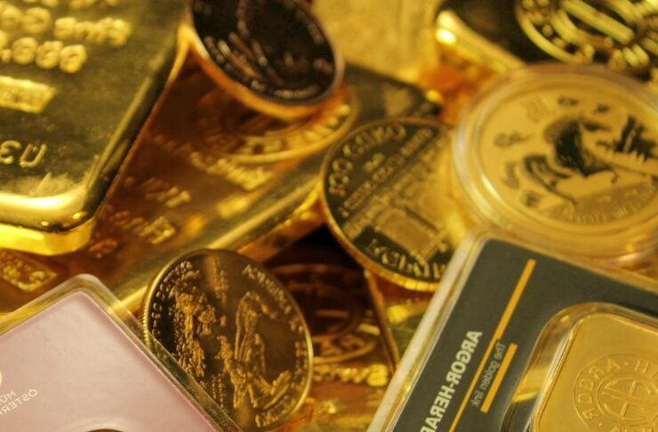 Pile of gold bars and coins, shiny and stacked, suggesting wealth and precious metal collection.