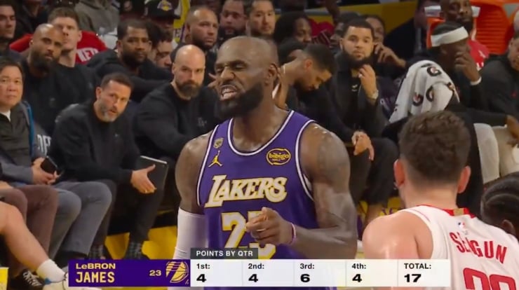 LeBron James in Lakers jersey gestures on court during a game, crowd behind him watching intently, scoreboard shows 17 points total for the game (Q1–Q4).