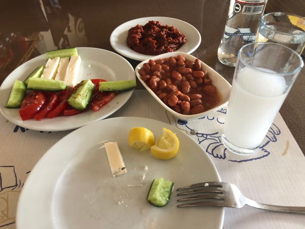 Plate with cucumber, tomato slices, and feta cheese sticks, plus a lemon twist on the edge of the plate—Mediterranean mezze setup