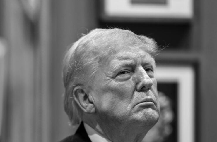 Older man in a dark suit and tie gazing upward with a serious expression; black-and-white portrait.