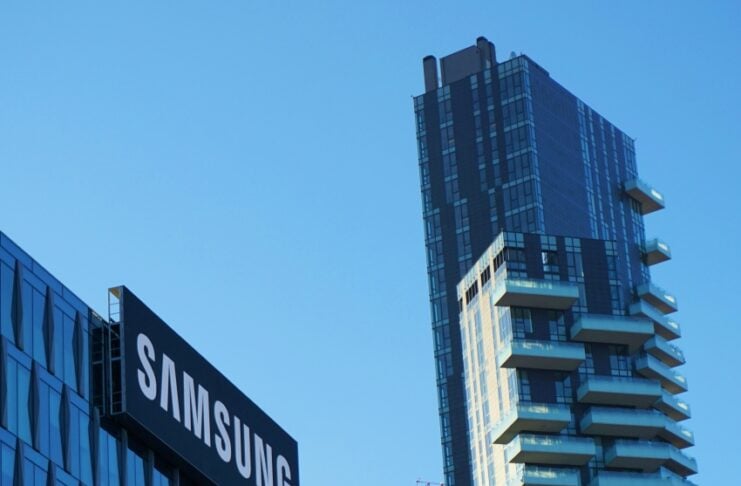 Samsung sign on a modern glass office building against a clear blue sky.