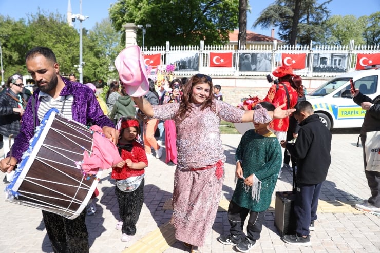 A street festival scene with a drummer, a woman in a pink dress dancing, and children watching, Turkish flags in the background.