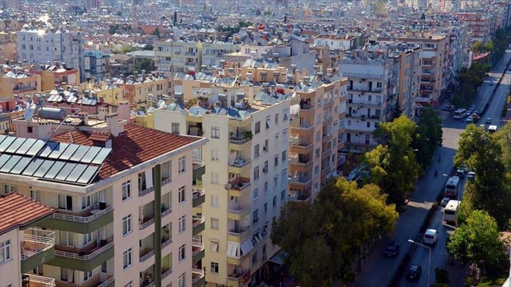 Dense urban neighborhood with mid-rise apartment buildings along a tree-lined street, rooftops and balconies visible.
