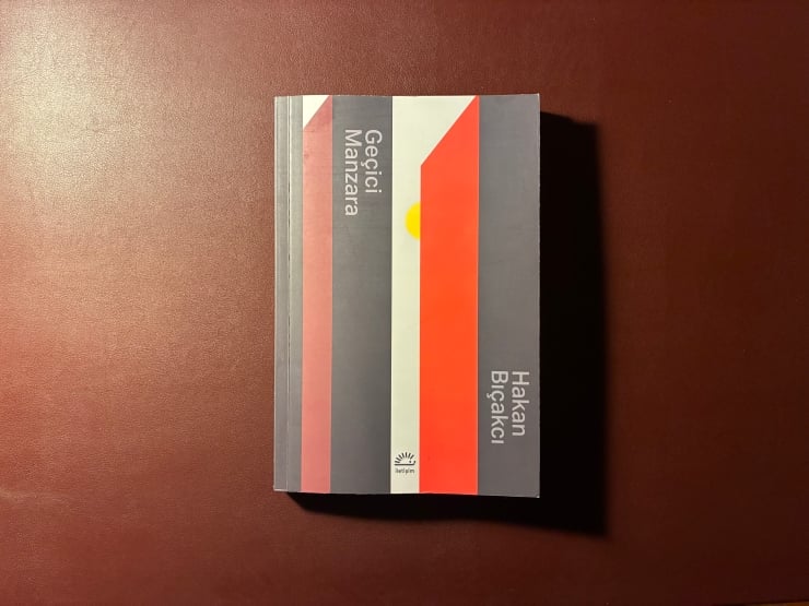 Top-down view of a closed book with a striped geometric cover on a brown table.