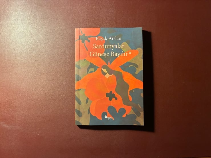Küçük kapaklı kitap; turuncu çiçekler ve mavi arka plan, başlık Sardunyalar Güneşe Bayılır, yazar Başak Arslan.