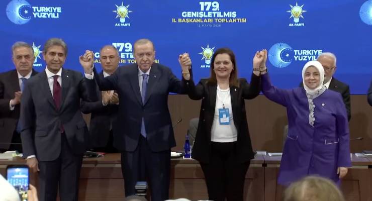 Group of politicians on a stage, raising their hands in a banner of unity at a Turkish party event, blue backdrop with logos behind them