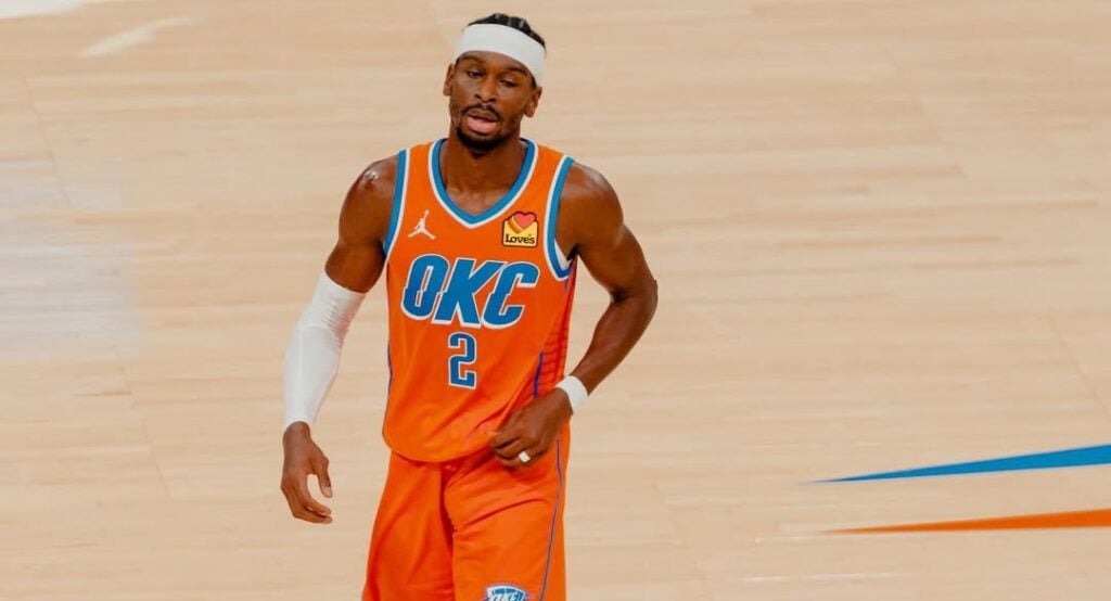 Basketball player in an orange Oklahoma City Thunder jersey with number 2, white headband and sleeve on his left arm on a basketball court