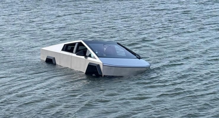 Futuristic silver car partially submerged in calm shallow water near the shoreline, angled with its front end in the sea, exterior intact.