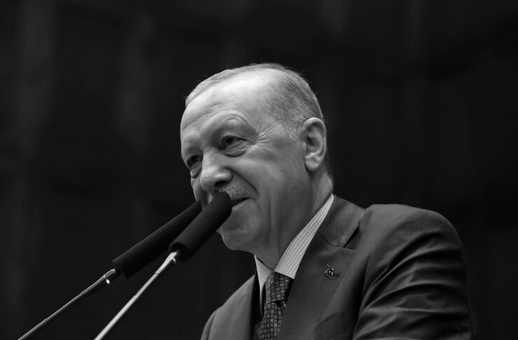 Man in a suit delivering a speech at a podium with two microphones in a formal setting (black and white).