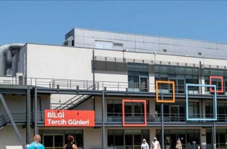University building with colorful square frames and a red banner reading 'BİLGİ Tercih Günleri'; people walk along a red pedestrian path outside the entrance.