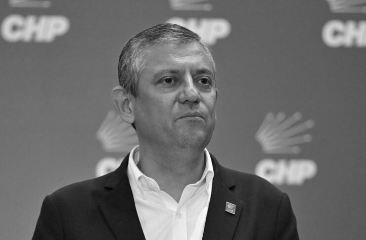 Turkish politician in a dark suit speaks at a press conference with microphones in front and CHP logos in the background.