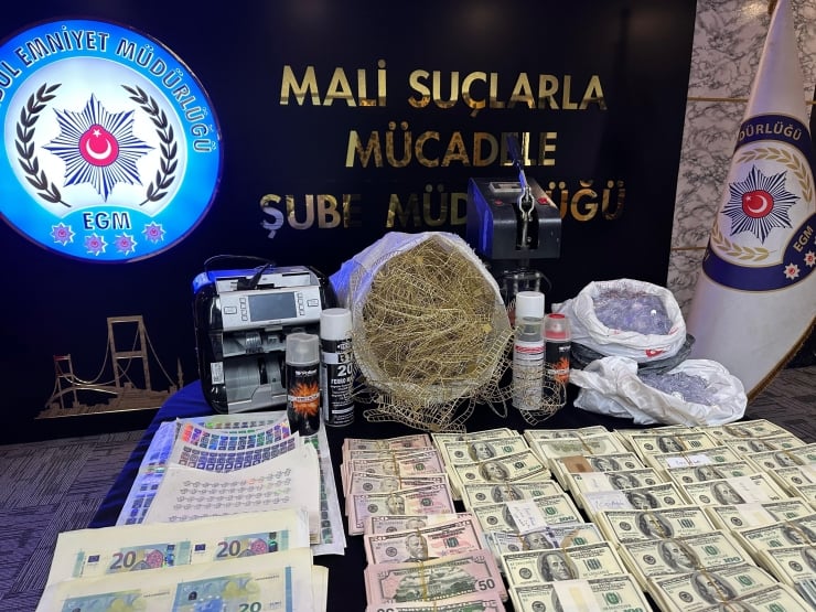 Display of seized evidence by Turkish police: large stacks of euro and US dollar bills, drug paraphernalia, and related lab supplies on a table in front of police emblems and a sign reading 'Mali Suçlarla Mücadele Şube Müdürlüğü'