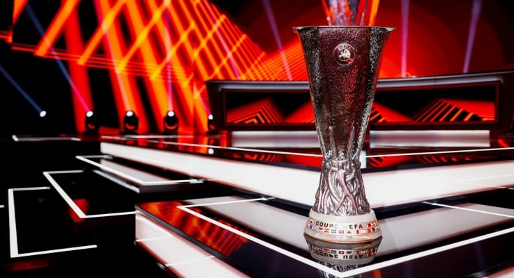 Shiny silver trophy on a futuristic stage with red neon lights and white steps in the foreground.