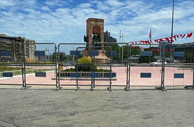 Barrier fencing labeled POLIS blocks access to a plaza with a brick arch monument in the center.