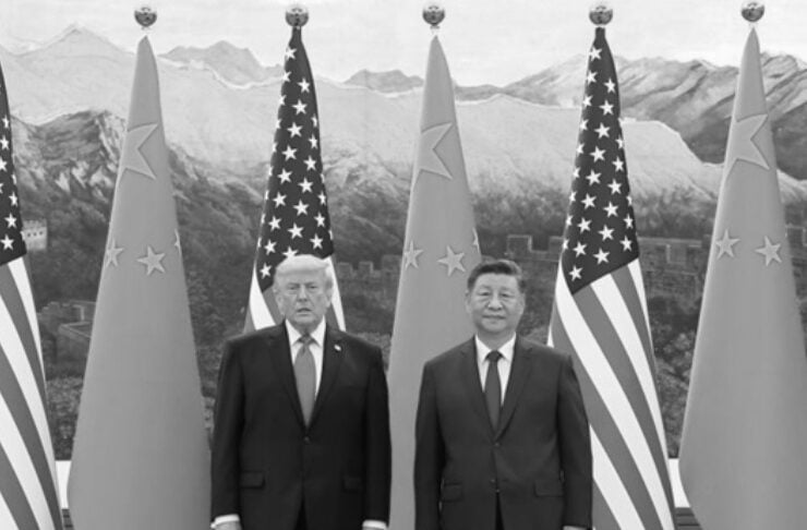 Two men in dark suits stand side by side in front of alternating U.S. and Chinese flags at a formal summit, grayscale photo.