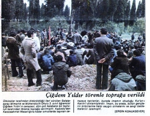 Outdoor funeral ceremony with a large crowd gathered around a dirt burial mound.