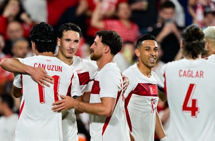 Turkish national soccer team players celebrate together on the pitch, embracing after a game.