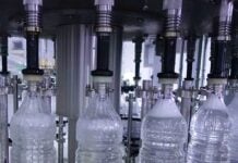 Industrial bottling line with clear plastic water bottles being filled by automated equipment in a factory setting
