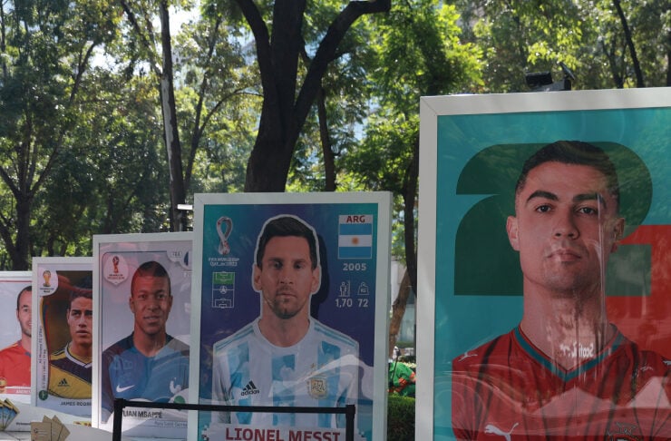 Outdoor display of oversized soccer player posters in a sunlit park, featuring Lionel Messi and Cristiano Ronaldo among others.