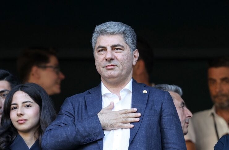 Man in a blue suit places his right hand over his chest, standing among a group of people.