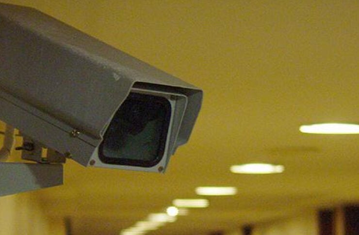 Security camera mounted in a dimly lit hallway, monitoring the corridor.