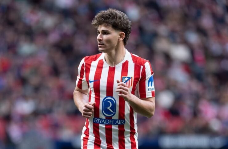 Atlético Madrid midfielder in red-and-white stripes and blue shorts, sprinting on the pitch during a match.
