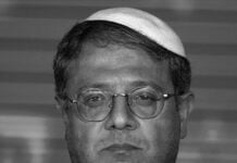 Man with a kippah and round glasses, wearing a suit and tie, looking straight at the camera.